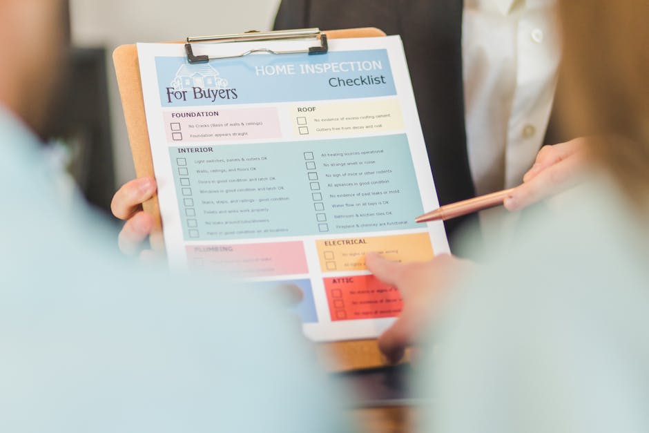 A person in a white shirt points to a home inspection checklist held on a clipboard during a house removal consultation. The checklist, titled 'Home Inspection Checklist for Buyers,' contains sections on foundation, roof, interior, plumbing, electrical, and attic, with some boxes marked or empty. The scene suggests a professional moving or packing assessment, with the individual discussing specific tasks related to home relocation. The background is blurred, focusing on the clipboard, which is held by another person with a light blue sleeve, indicating an indoor setting. This process is part of the planning stage for a house removal service, such as those provided by Man with Van Enfield Town, supporting efficient furniture transport and packing preparations during home relocation.